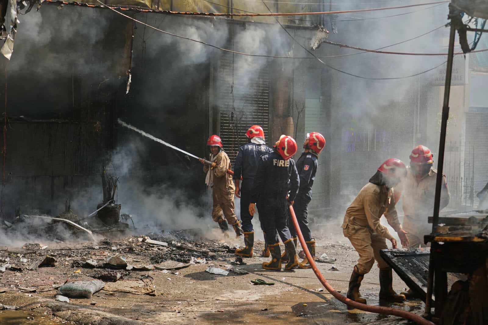 Firefighters battling a blaze amidst smoke and debris at a fire incident scene.