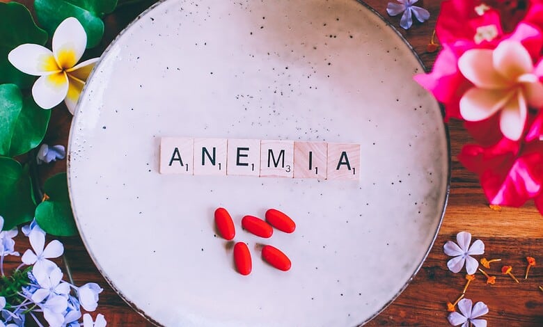 A plate with the word Amenia spelled out with letter tiles and red pills, surrounded by colorful flowers.