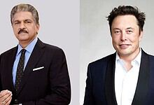 Two men in formal suits, one with grey hair and mustache, the other with dark hair, smiling.