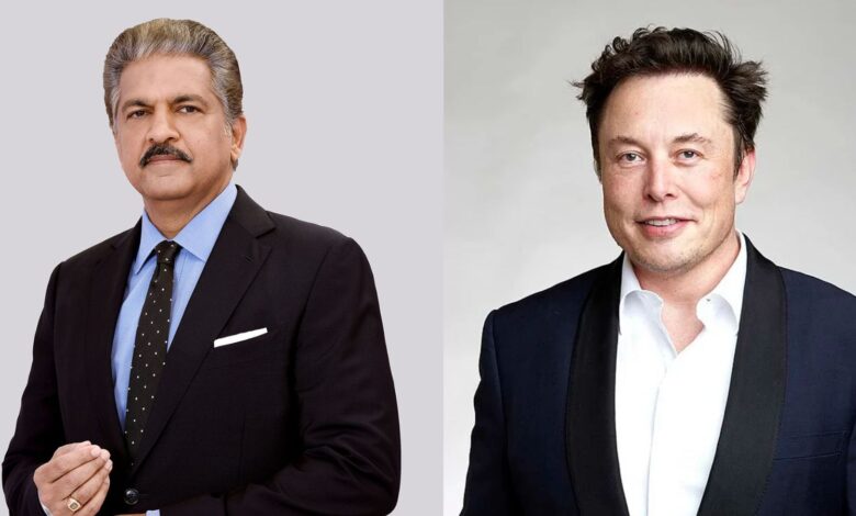 Two men in formal suits, one with grey hair and mustache, the other with dark hair, smiling.
