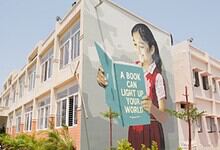 Colorful mural of a girl reading a book on the school wall, promoting education and literacy.