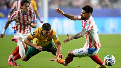 Australian and Paraguayan football players in action during a World Cup match.