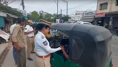 Police officers inspecting a green auto rickshaw on a busy street in India.