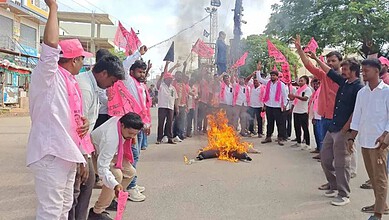 Protesters gather around a fire on the street during a demonstration, holding pink flags and banners in a.