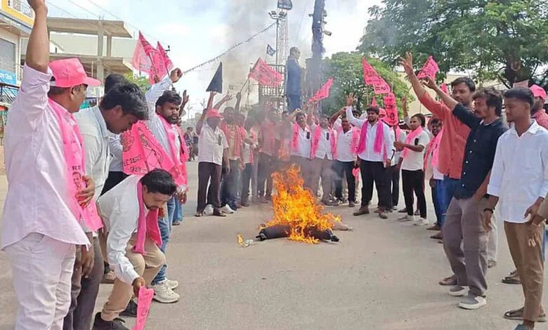 Protesters gather around a fire on the street during a demonstration, holding pink flags and banners in a.