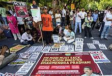 Protesters gather with signs and banners in a street demonstration in India.