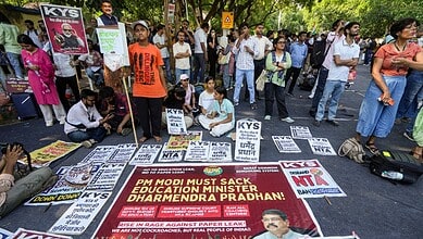 Protesters gather with signs and banners in a street demonstration in India.
