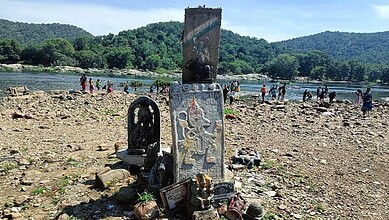 People enjoying a day at the Cauvery river with scenic green hills in the background.