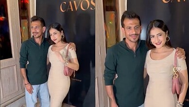 A well-dressed man and woman posing together at a social gathering, smiling and enjoying the event.
