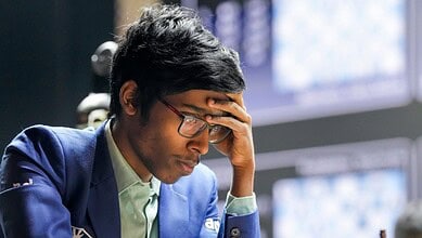 Young man in a blue suit appears stressed while working at a computer station.