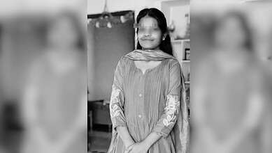 A woman wearing traditional attire, smiling, indoors in a casual setting.