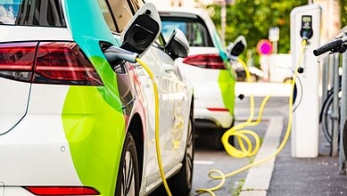 Electric vehicle charging station with cars plugged in at an outdoor charging point.