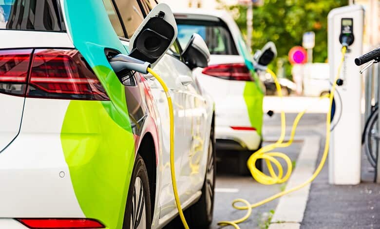 Electric vehicle charging station with cars plugged in at an outdoor charging point.