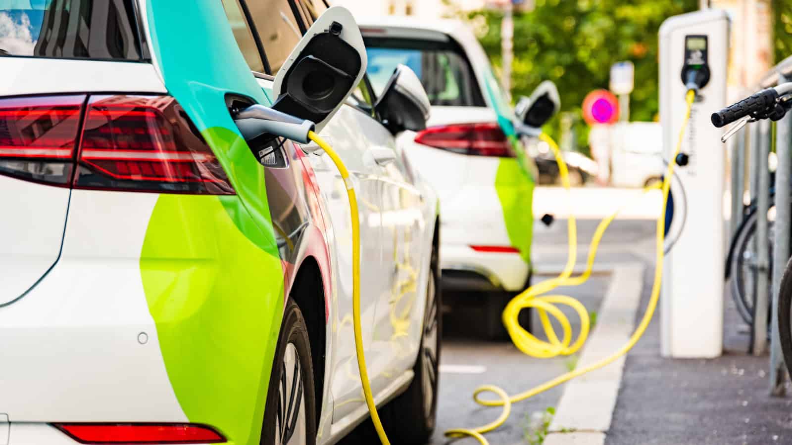 Electric vehicle charging station with cars plugged in at an outdoor charging point.