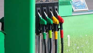 Refuelling station with green, yellow, and red fuel nozzles at a petrol pump.