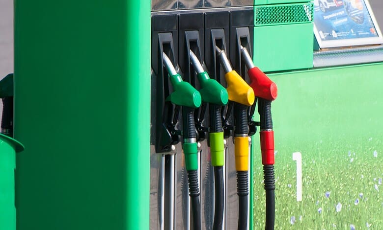 Refuelling station with green, yellow, and red fuel nozzles at a petrol pump.