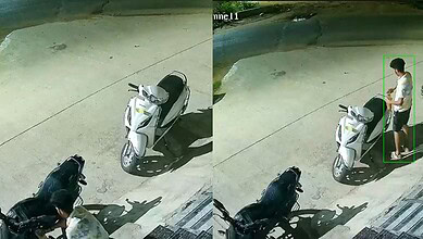 Young man standing next to a white scooter on a street at night.