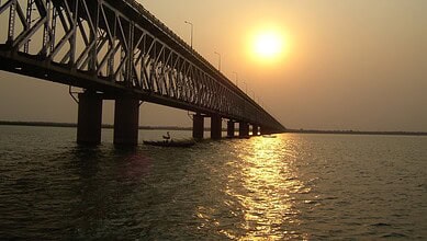 Bridge over Godavari River at sunset with a boat in the water.