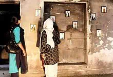 A woman viewing framed photographs displayed on a weathered wall in an indoor setting.
