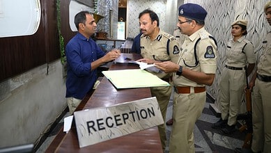 Police officers engaging with a visitor at the reception desk in a government or institutional setting.