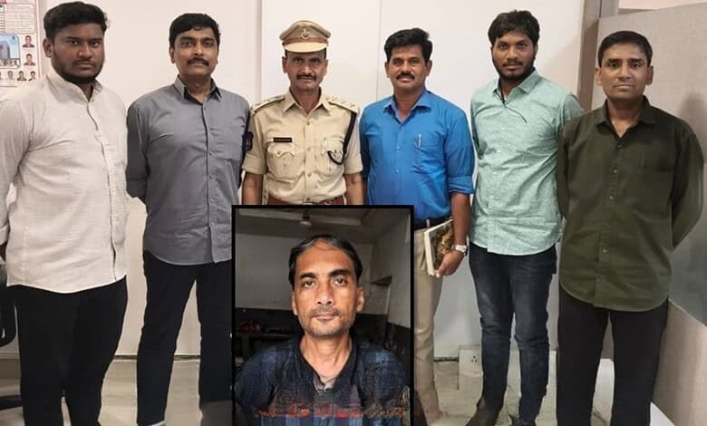 A man in a black shirt is photographed with six men, including a police officer, in an indoor setting.
