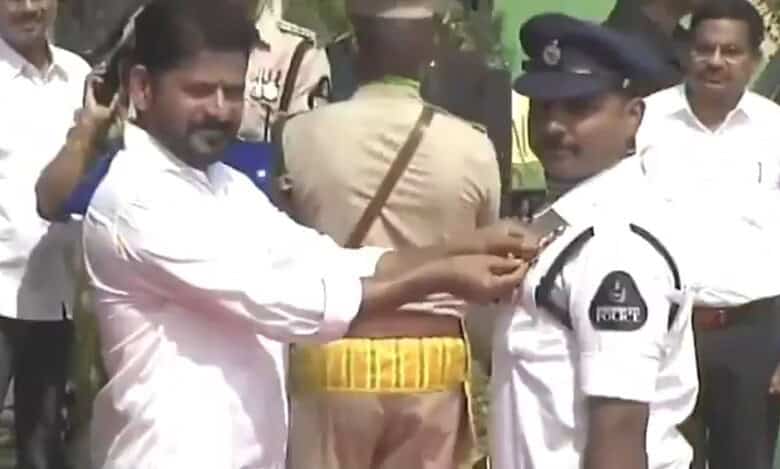 Man pinning badge on police officer during a public event, with onlookers and officials present in the ba.