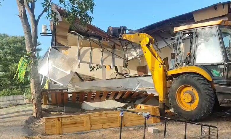 Excavator demolishing a building on a sunny day in Hyderabad.