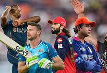 A cricket team celebrating on the field after a match, with players in colorful uniforms and a stadium ba.