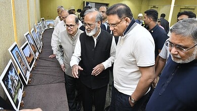Prominent officials viewing landscape photographs at an indoor exhibition event.
