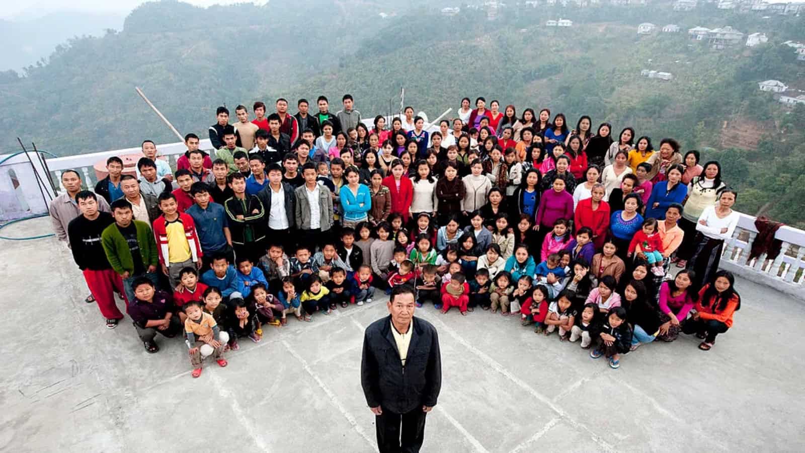 Group of diverse people gathered outdoors on a mountain terrace, posing for a photo.