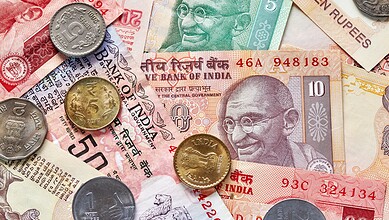 Indian currency notes and coins, including rupees and paise, on a surface.