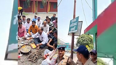 A group of people sitting on the ground around a traditional fire cooking setup outdoors, with police off.