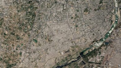 Satellite image of a city with a river running through it, showing urban and green areas.
