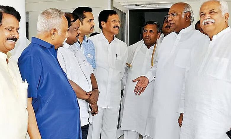 A group of Indian men engaged in a discussion indoors, dressed in traditional and formal attire, with a f.
