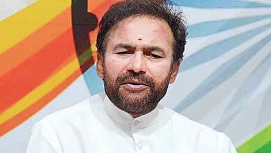Kishan Reddy speaking at a press conference with Indian flag colors in background.