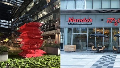 A vibrant red sculpture outside a modern building with Nando's restaurant signage.