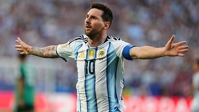 Lionel Messi celebrating with arms outstretched during a match in Argentina's national team jersey.