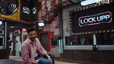 Contestant in Lock Upp 2 house tour, smiling in a colourful, industrial-style set.