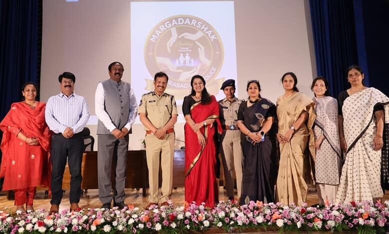 Empowered women and officials at the Naragadashak event on stage with a floral display in front.