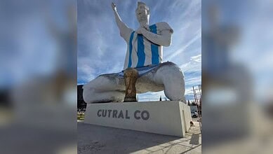 Giant statue of Messi in a blue and white striped jersey with one arm raised.