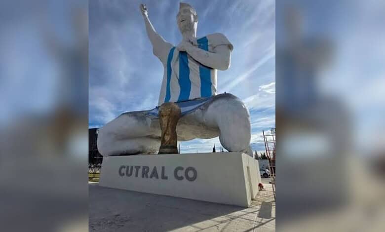 Giant statue of Messi in a blue and white striped jersey with one arm raised.