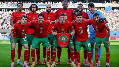 Moroccan football team in red jerseys on the field during a match at the FIFA World Cup.