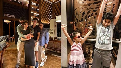 Family of four with two children, smiling and celebrating in a hotel lobby with warm lighting and modern.