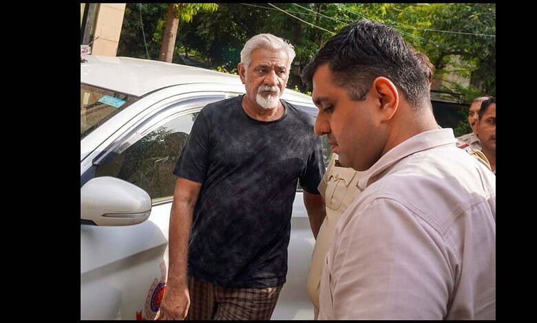 A man in a white shirt talking to an older man with a beard and black t-shirt outdoors.