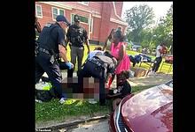 A woman receiving first aid from emergency responders on a sidewalk outside a house.