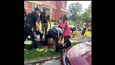 A woman receiving first aid from emergency responders on a sidewalk outside a house.