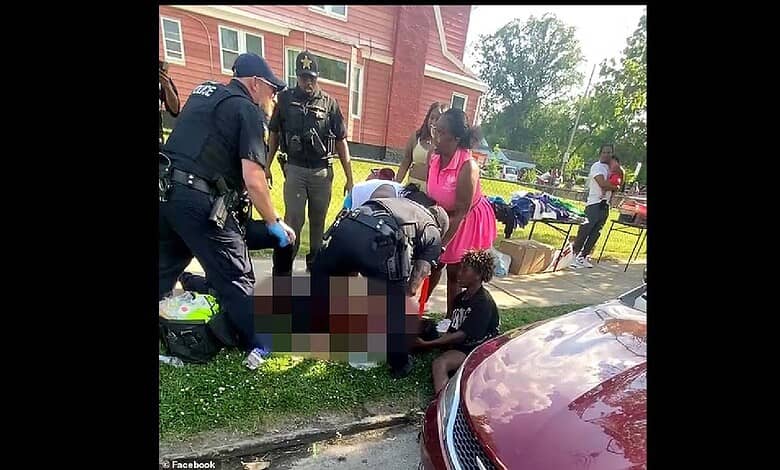 A woman receiving first aid from emergency responders on a sidewalk outside a house.