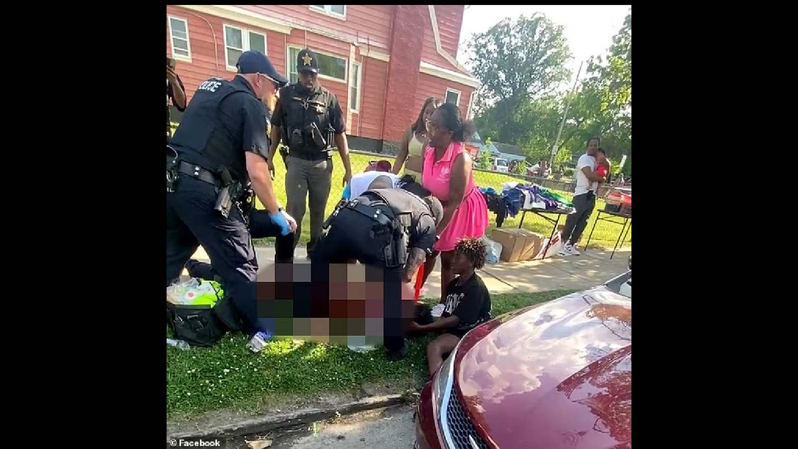 A woman receiving first aid from emergency responders on a sidewalk outside a house.
