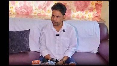 A young man in a white shirt sitting on a sofa during an interview at The Siasat Daily.