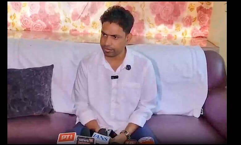 A young man in a white shirt sitting on a sofa during an interview at The Siasat Daily.